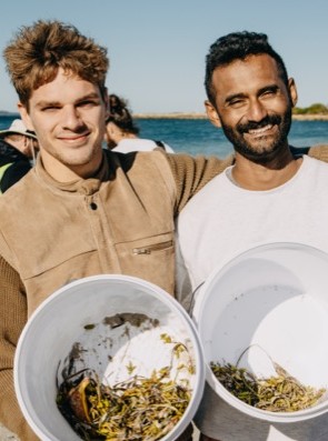 Two youth volunteers collecting marine seeds as part of a beach volunteering day